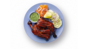 A plate of tandoori chicken with mint chutney