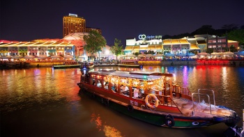 A bumboat with a night scene of Clarke Quay in the background