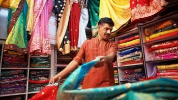 An Indian man laying out colourful saris for display at Little India Arcade