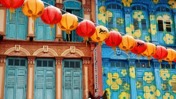 A line of red and orange lantern lined up at Chinatown with a shophouse backdrop