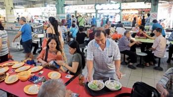 Foto seorang lansia memegang nampan makanan di Chinatown Complex Food Centre