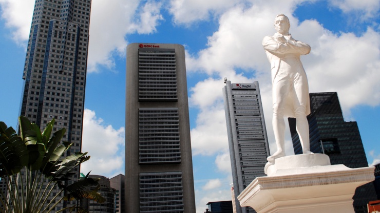Patung Stamford Raffles berlatar lanskap kota Singapura