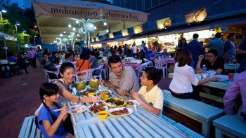 ภาพมุมกว้างของครอบครัวที่กำลังรับประทานอาหารกันที่ Makansutra Gluttons Bay