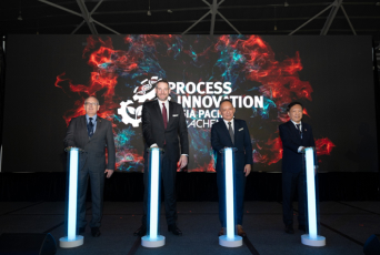 Four men on stage gathering with glowing pillars before them, with Process Innovation Asia-Pacific on screen.