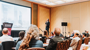 Speaker at Council on Tall Buildings and Urban Habitat International Conference showing a presentation on stage, about the future of urban living.