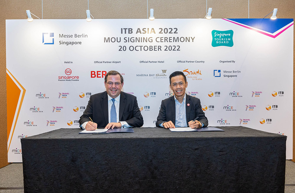 MOU signing between two smiling men at ITB Asia 2022 to exchange knowledge and ideas.