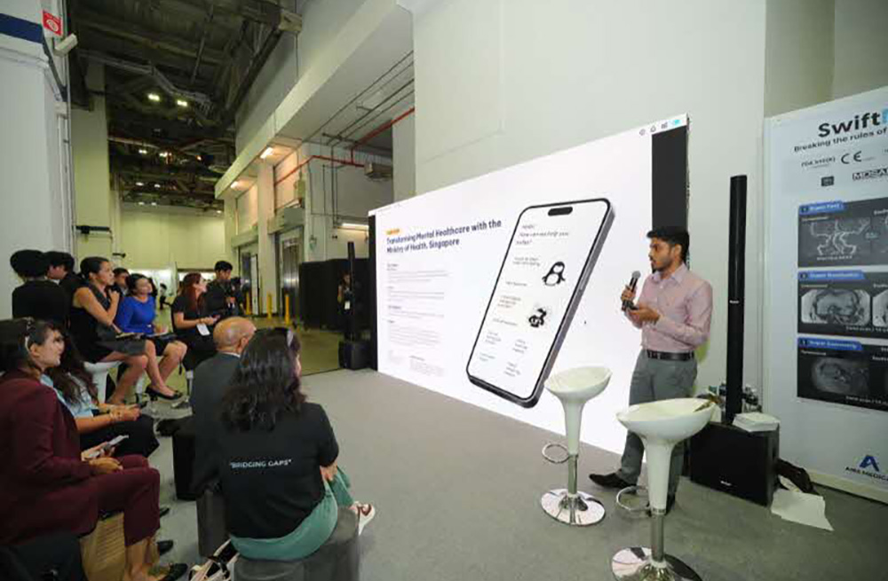 Young presenter showcasing a mental health app at a medical conference, with an engaged audience and screen features.