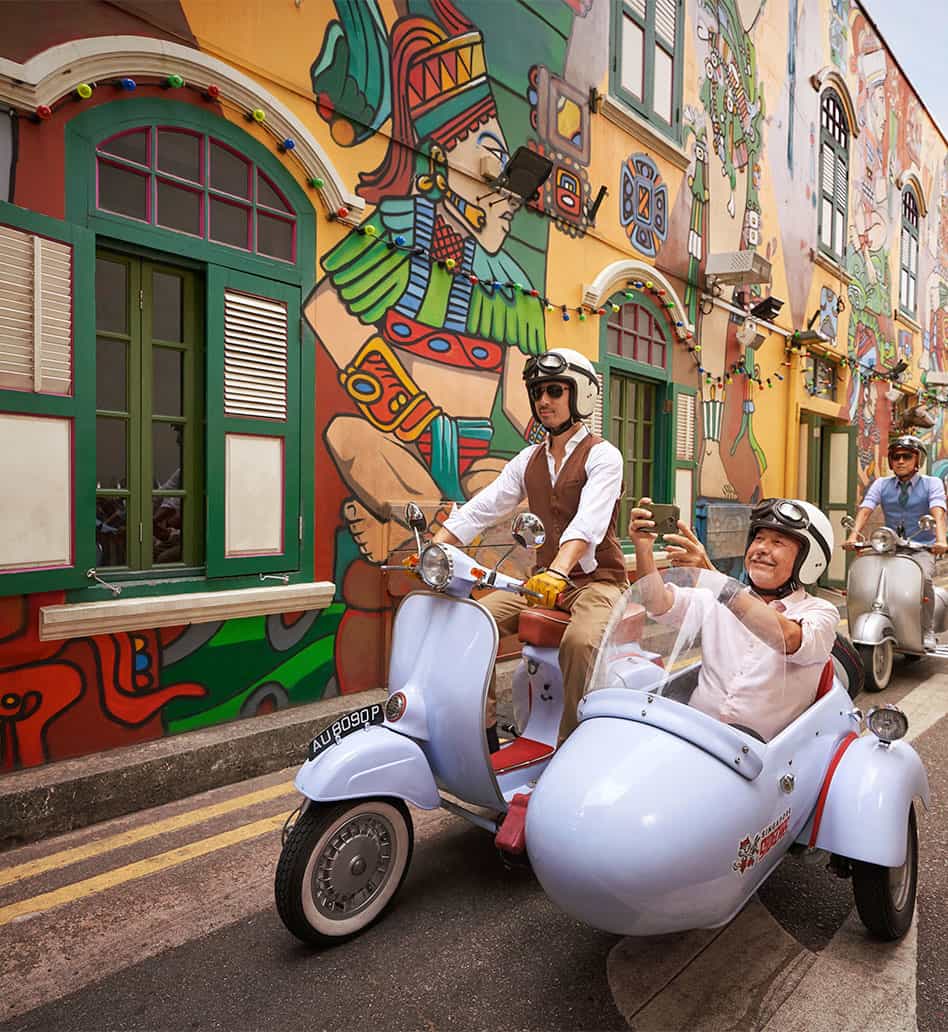 People riding Vintage Vespa with sidecar