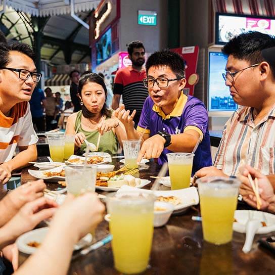Friends engaging in Singapore Street Food and Night Tour