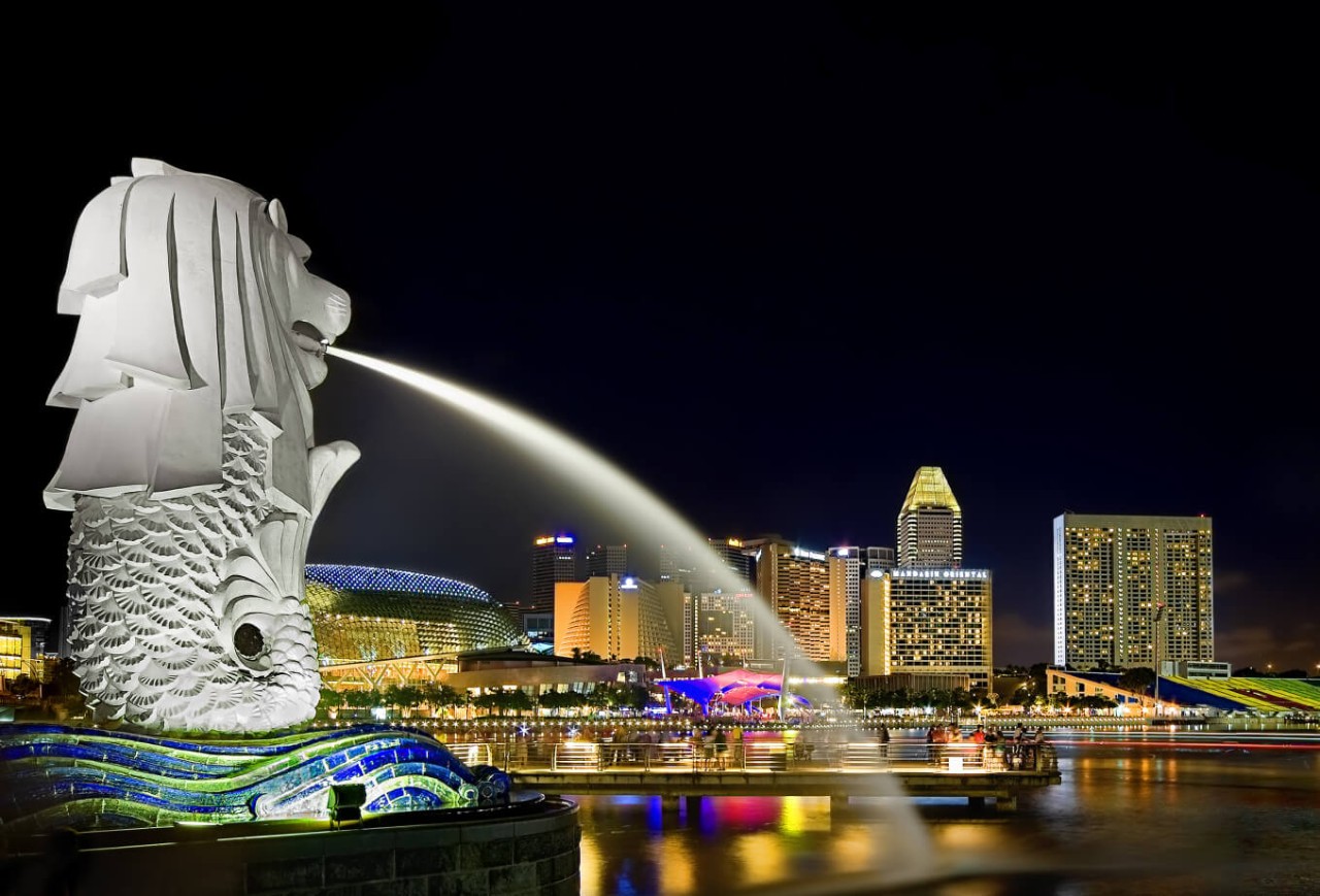 Merlion Park Singapore illuminated at night with Marina Bay city skyline reflected on the water