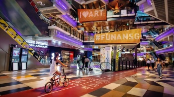 Junge Frau beim Fahrradfahren in der Funan IT Mall Singapore