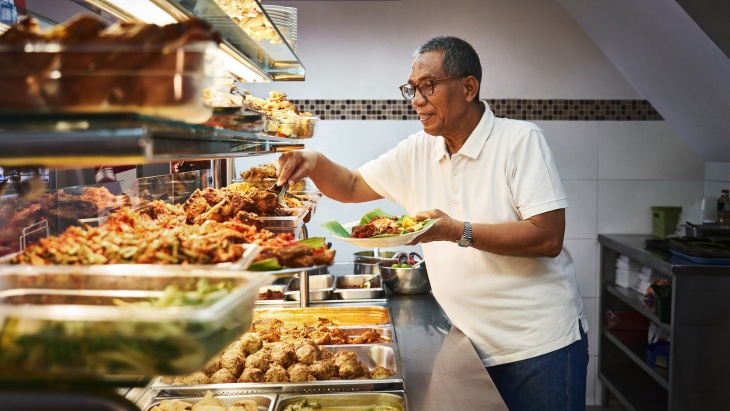 Wirt des Warung Nasi Pariaman Nasi Padang in Kampong Gelam bereitet Essen zu