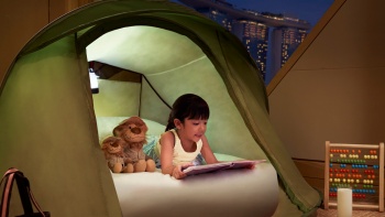 Ein Mädchen in einem Zelt, das ein Buch im The Ritz-Carlton, Millenia Singapore liest