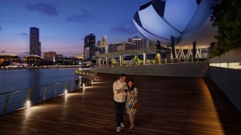 Ein Paar auf einer Brücke mit dem ArtScience Museum™ im Hintergrund.