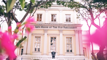 Außenansicht des Arts House mit rosafarbenen Blumen vor der Fassade. 