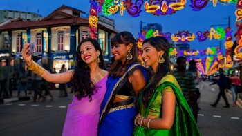 Inderinnen posieren für Fotos vor der Deepavali-Festbeleuchtung in Little India
