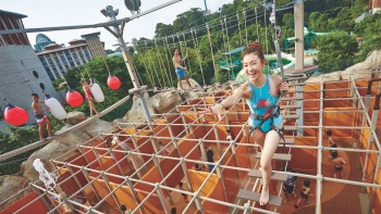 Ein Mädchen im Badeanzug, das im Wet Maze des Adventure Cove Waterpark klettert 