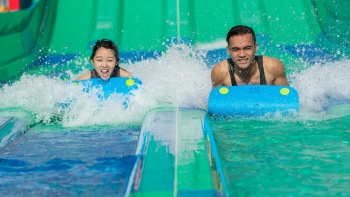 Ein Mädchen und ein Junge rutschen die Wasserrutsche Kraken Racer im Wasserpark Wild Wild Wet hinunter