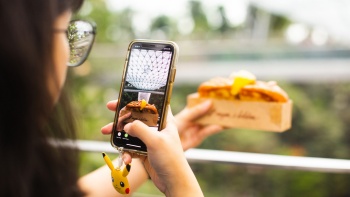 Besucher im Jewel Changi Airport fotografiert eine Lobster Roll im Burger and Lobster