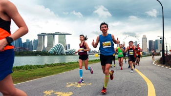 Läufer beim Standard Chartered Marathon mit Cloud Forest und Marina Bay Sands<sup>®</sup> im Hintergrund