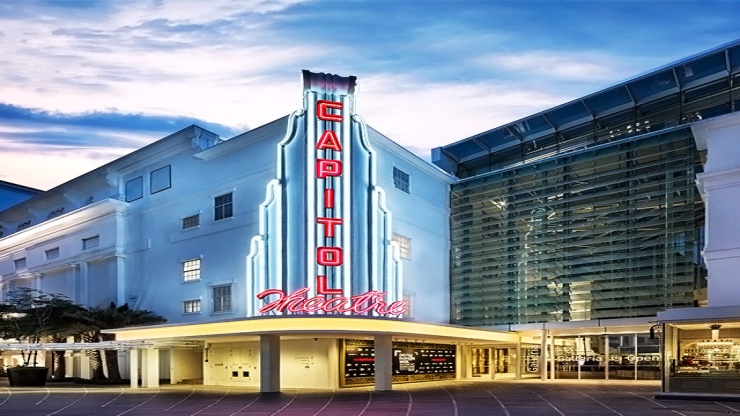 Abendaufnahme des Capitol Theatre neben dem Capitol Singapore vor blauem Himmel