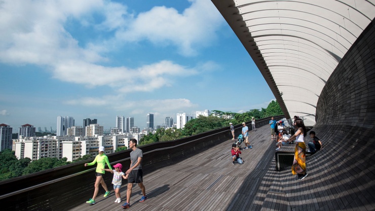 Aufnahme einer Familie, die die Henderson Waves entlang schlendert, mit HDB-Wohnungen im Hintergrund. 