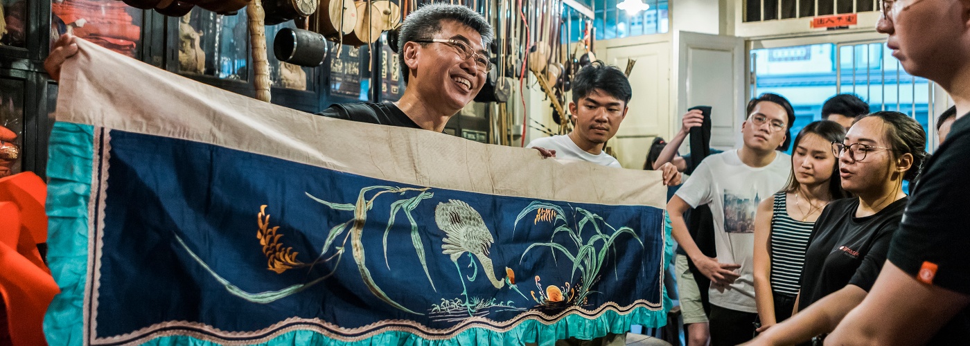 Ein Mann vom Eng Tiang Huat Chinese Cultural Shop hält ein Banner, das für die chinesische Kultur und Wandteppiche wirbt 