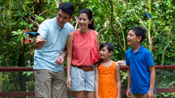 Family of four interacting with a bird at an exhibit in Jurong Bird Park in Singapore