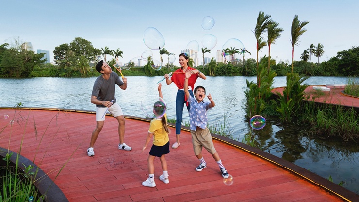 Eine Familie spielt mit Seifenblasen auf dem Bohlenweg Rasau Walk in den Jurong Lake Gardens