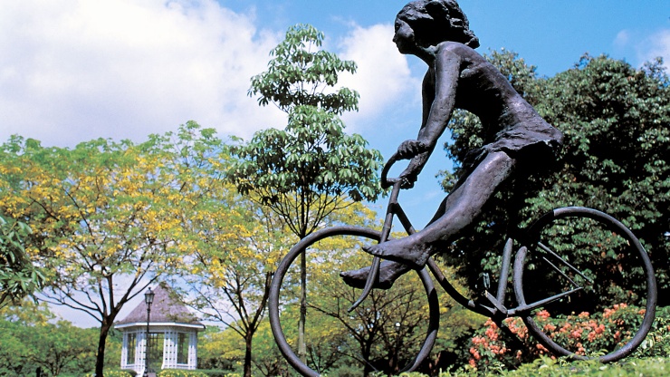 Weitwinkelaufnahme einer Statue im Botanischen Garten von Singapur mit dem charakteristischen Pavillon im Hintergrund
