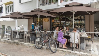 Eine Gruppe von Freunden genießt das Frühstück im Open-Air-Bereich des Baker & Cook im Holland Village 