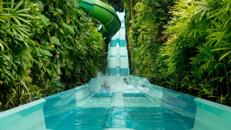 Kinder spielen auf der Wasserrutsche im Adventure Cove Waterpark in der Resorts World™ Sentosa