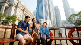 Eine Familie auf einem Bumboat bewundert die Skyline Singapurs am Tag