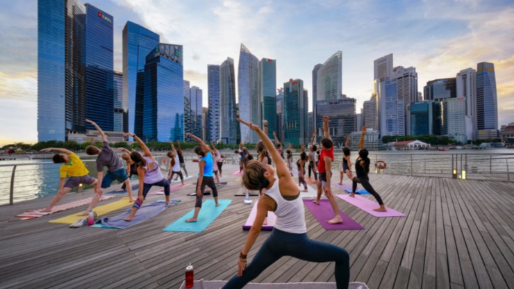 Eine Menschengruppe macht Yoga mit der Singapurer Skyline im Hintergrund