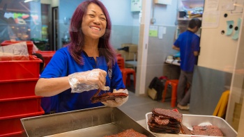 Eine Dame verpackt Bak Kwa (Trockenfleisch) bei Lim Chee Guan 