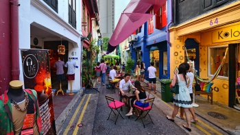 Farbenfrohe Shophouses auf der Haji Lane mit Gästen, die unter freiem Himmel essen