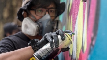 Nahaufnahme eines Manns, der Graffiti auf eine Wand sprüht