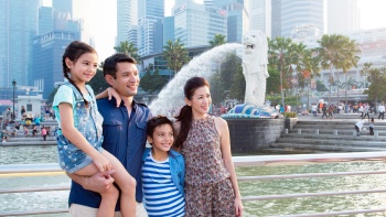 Eine junge eurasische Familie posiert für ein Foto im Merlion Park 