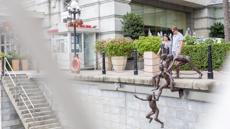 Touristen schauen sich die „People of the River“ Skulpturen an