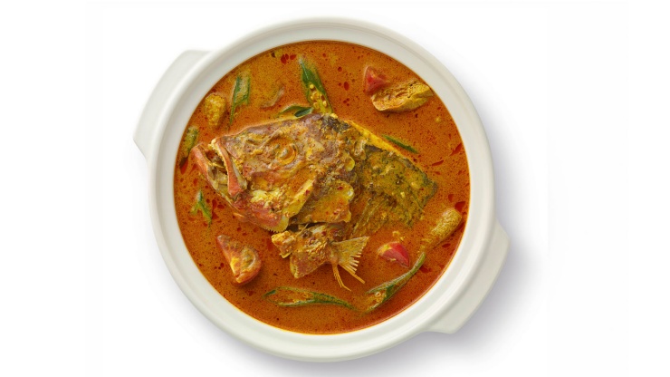 Flat lay of a pot of fish head curry cooked with vegetables and spices