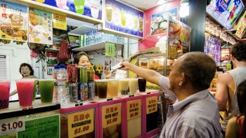 An elderly man buying drinks from a streetside drinks stall at Bugis Street