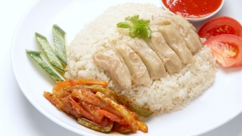 A close up shot of a plate of chicken rice with chilli sauce and nyonya pickles