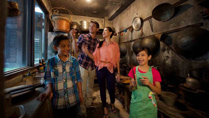 Young family exploring a mock kitchen circa 1950s, recreated at the Chinatown Heritage Centre