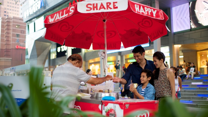 Young family buying ice-cream from a roadside vendor outside Orchard Road, Wisma Atria