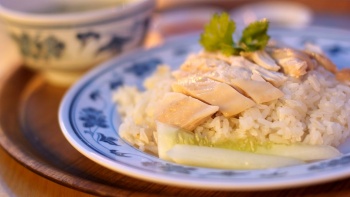 A plate of local chicken rice, served with clear soup in the background