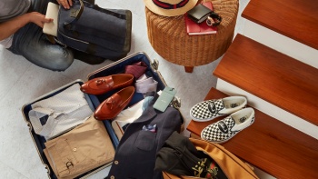 Flatlay of menswear products in a suitcase featuring local designer brands against a neutral background.