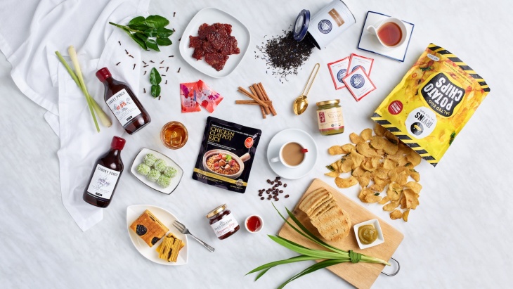 A flatlay of edible Singapore souvenirs such as IRVINS Salted Egg Fish Skins and The 1872 Clipper Tea Co.