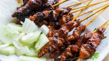 A plate of satay with cucumber slices