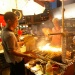 A tourist looking at a street hawker grilling satay at Lau Pat Sat