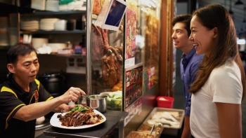Young woman ordering duck rice at a hawker stall